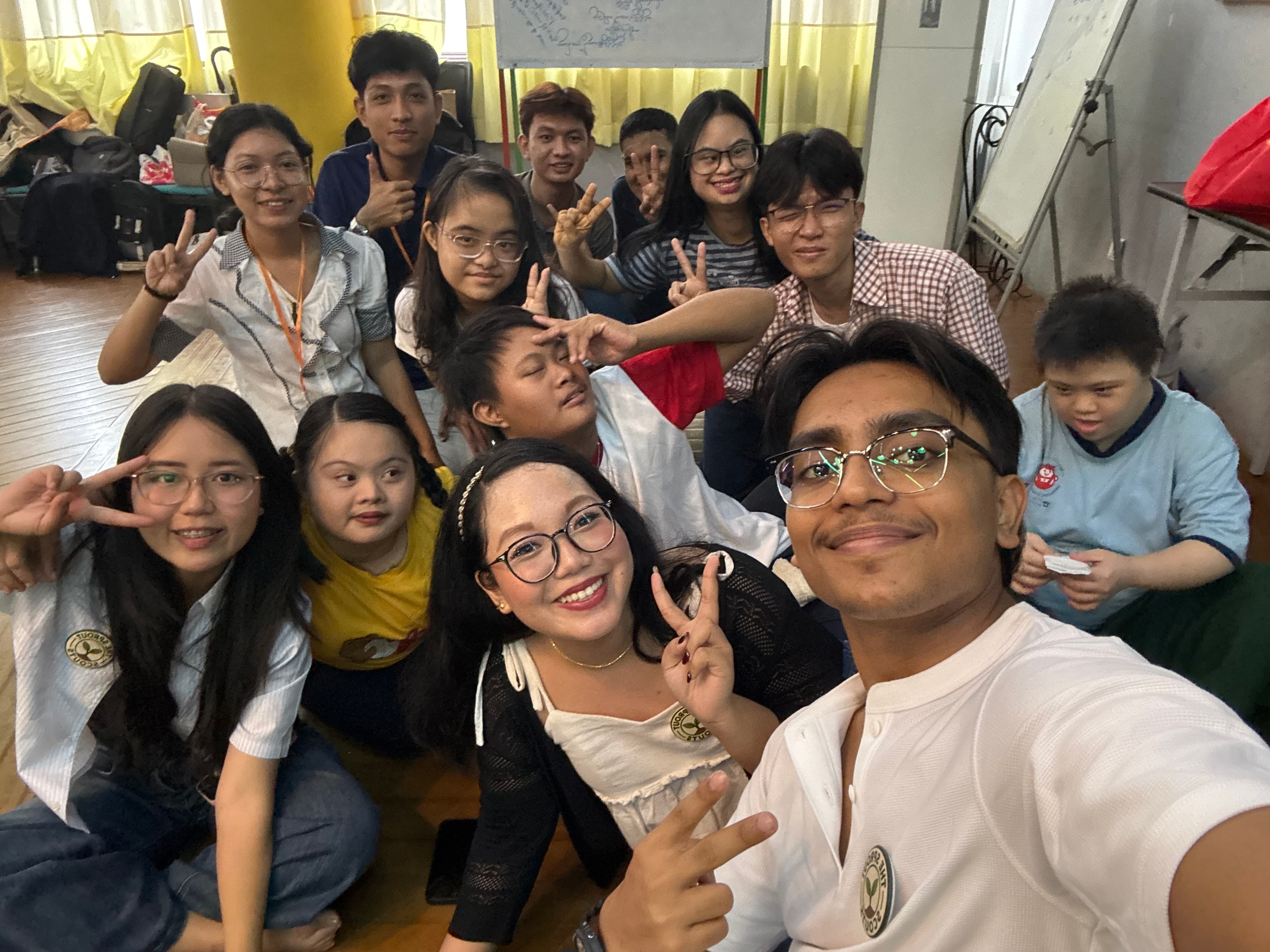 Group selfie of volunteers and participants sitting on the workshop floor