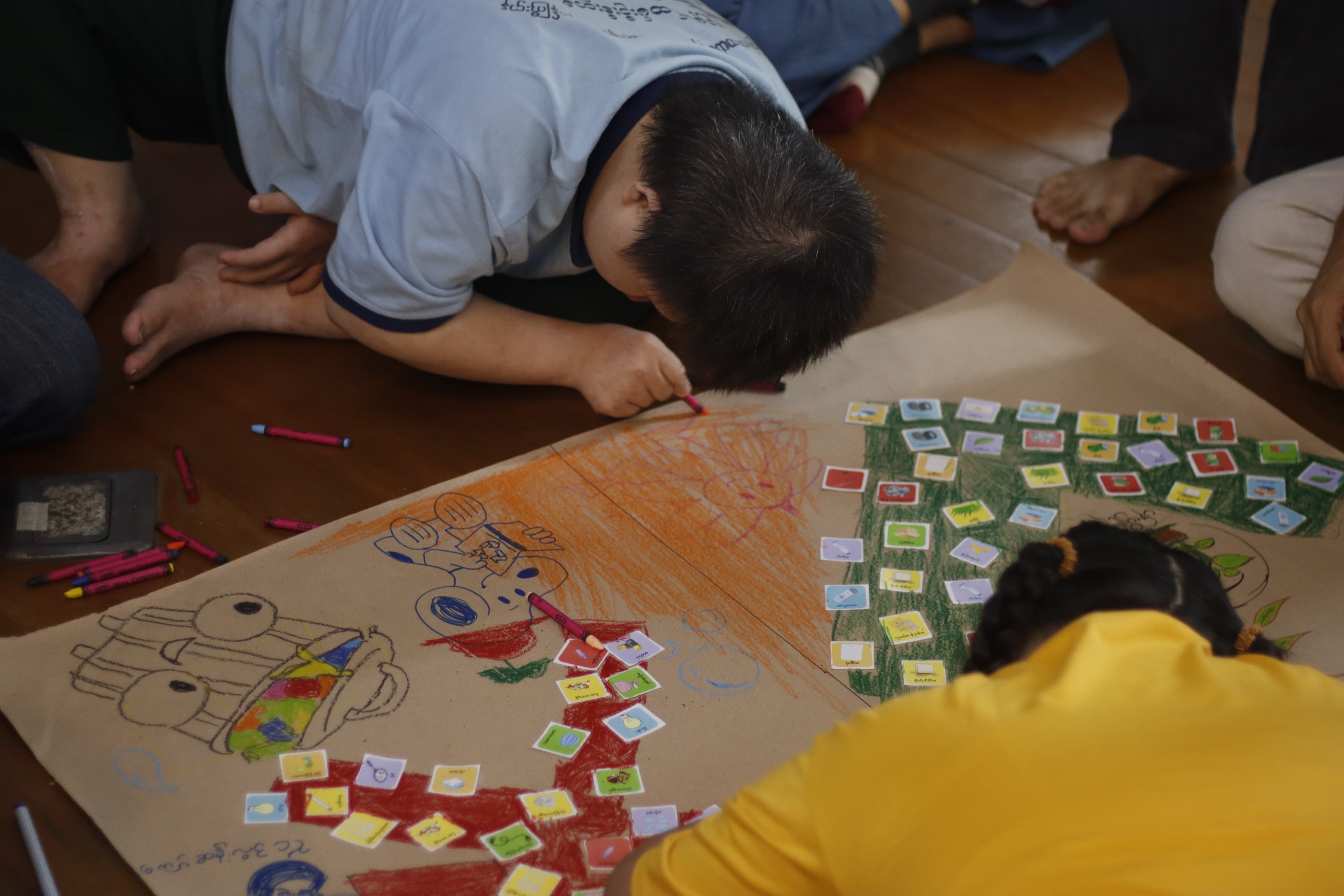 Participants drawing and placing stickers on a workshop craft poster