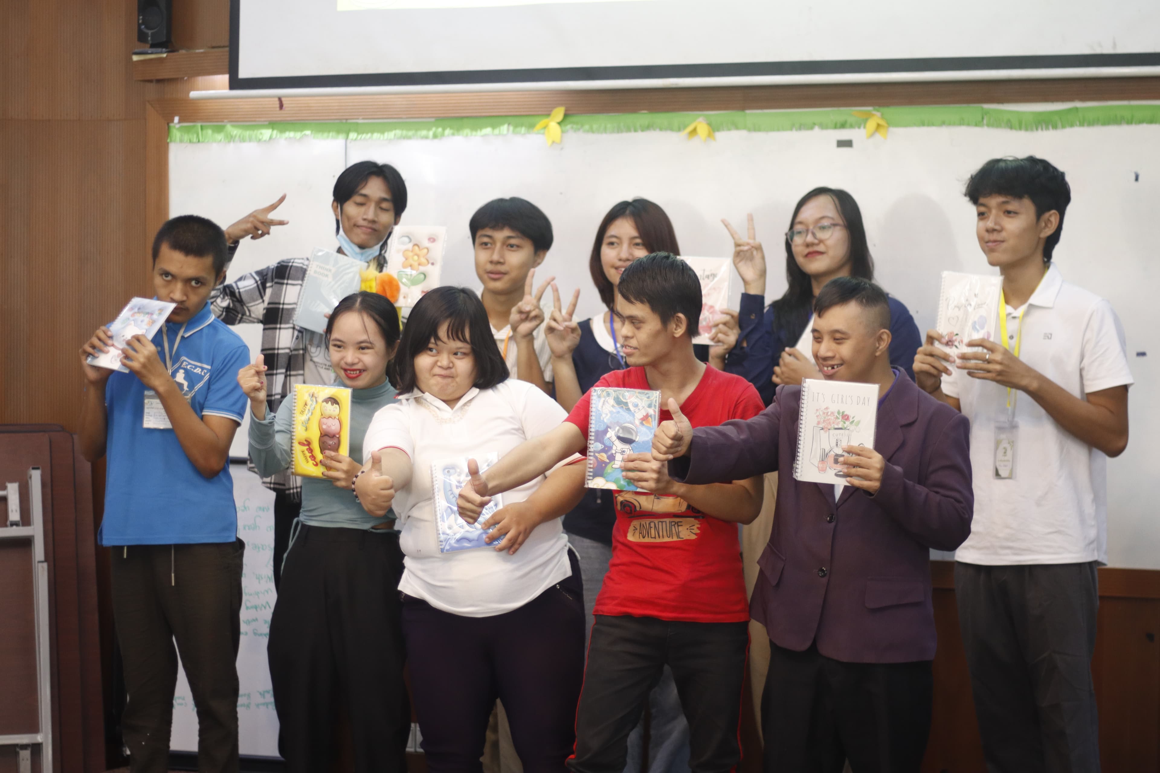 Participants holding notebooks and giving thumbs up after the session
